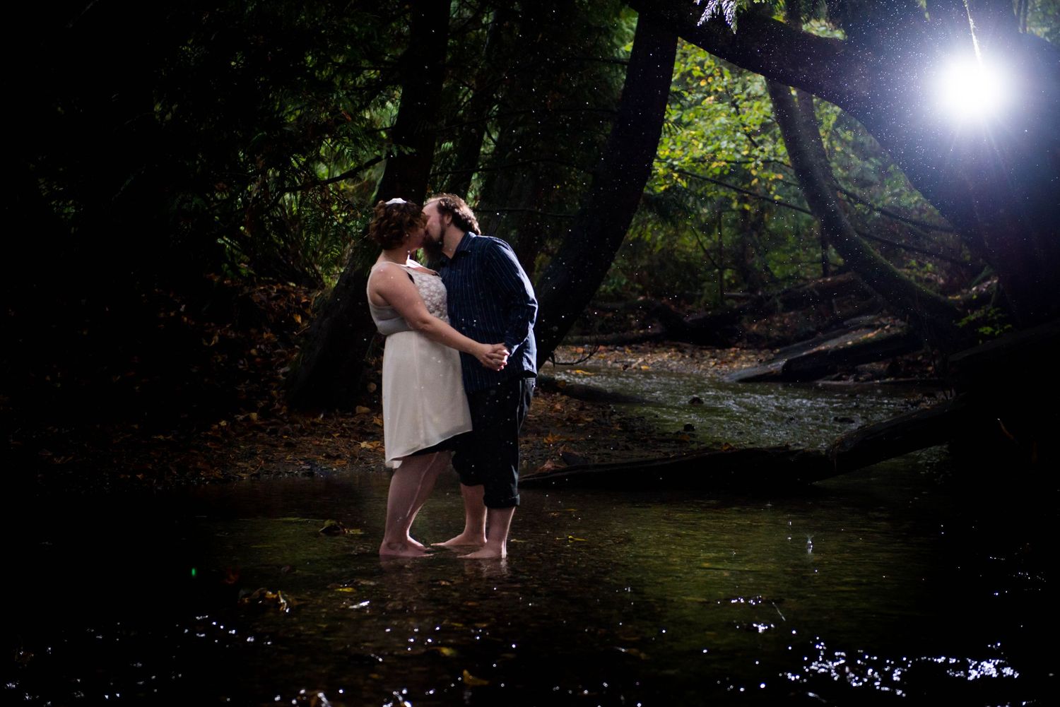 Couple kissing in a forest creek during an evening engagement session in Abbotsford, British Columbia.