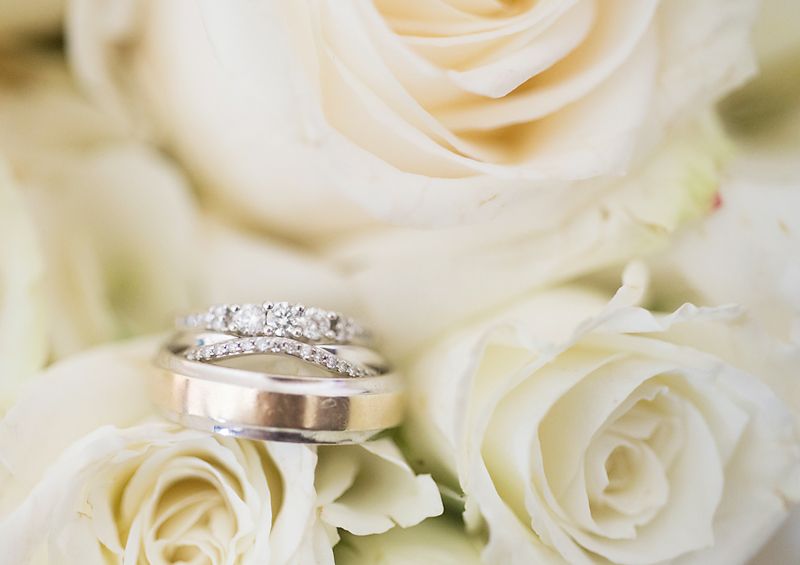 Wedding rings rest on white roses, capturing an elegant detail from a wedding celebration in British Columbia.