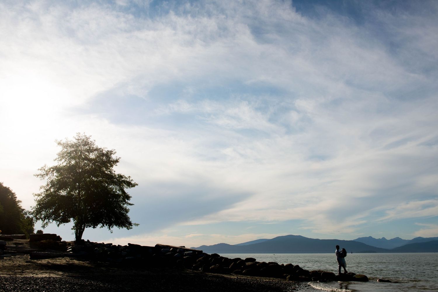 Couple silhouetted against a waterfront and mountain landscape in Vancouver, British Columbia.