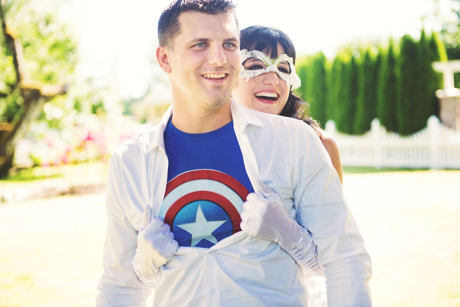 Couple smiling together during their wedding portraits as the bride reveals her groom's Captain America T-shirt.