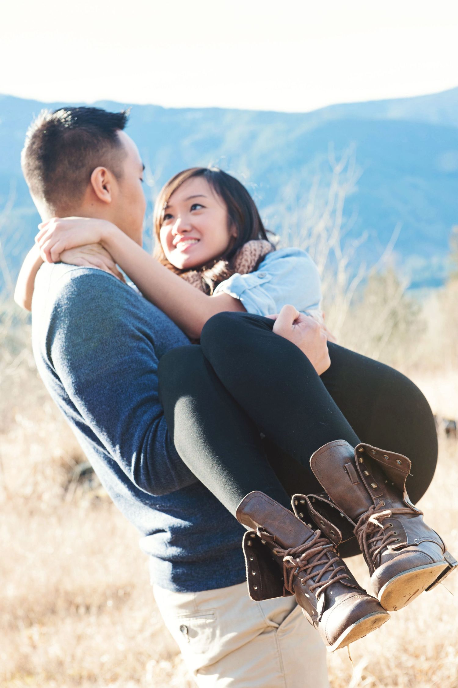 Man carrying his partner through a golden field during an engagement session in Chilliwack, British Columbia.