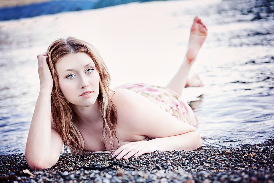 Portrait of a young woman lying on the rocky shoreline at Cultus Lake, British Columbia.