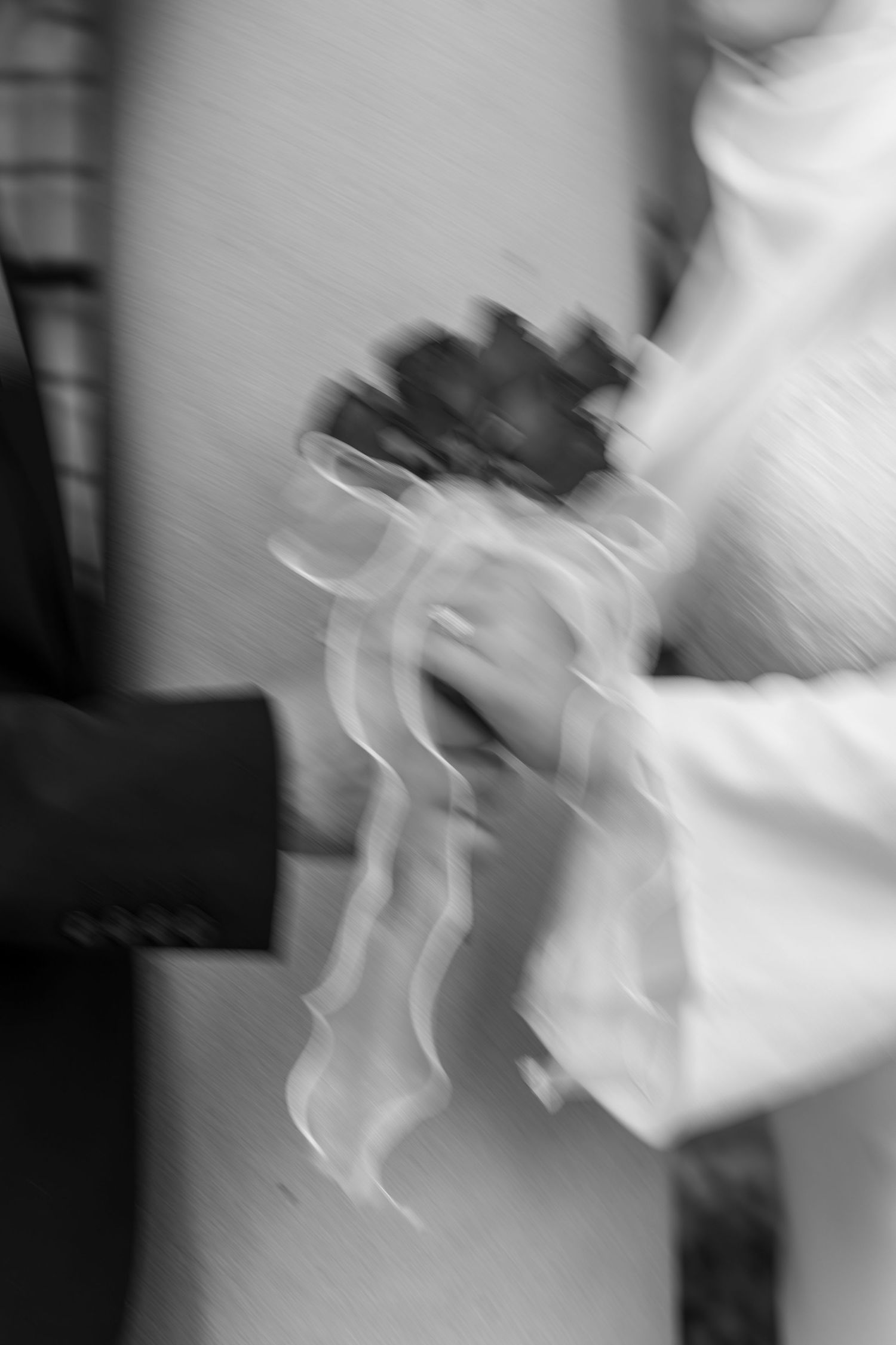 Blurred black and white photo of bride and groom exchanging rings during wedding ceremony.
