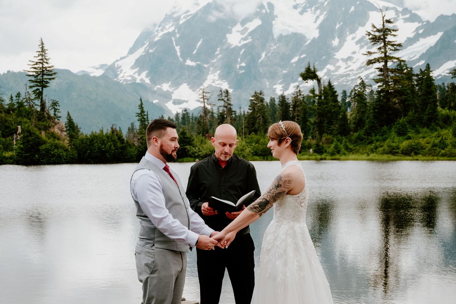 Mountain lake wedding ceremony with snowy peaks in background.