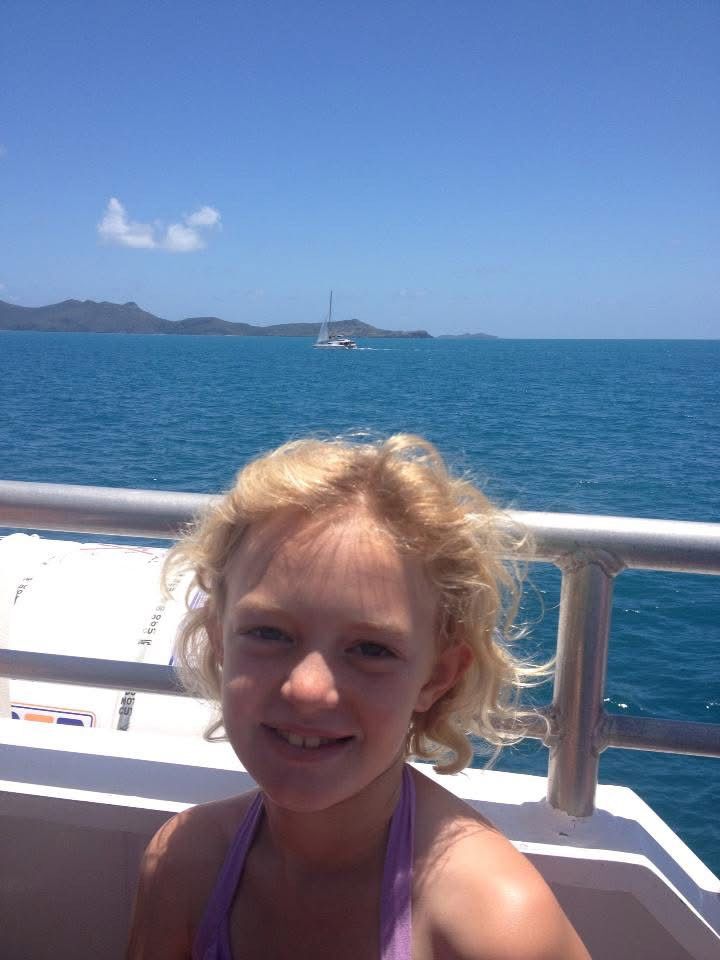 A scenic boat trip shows blue ocean waters and distant mountains under clear skies on a sunny day.