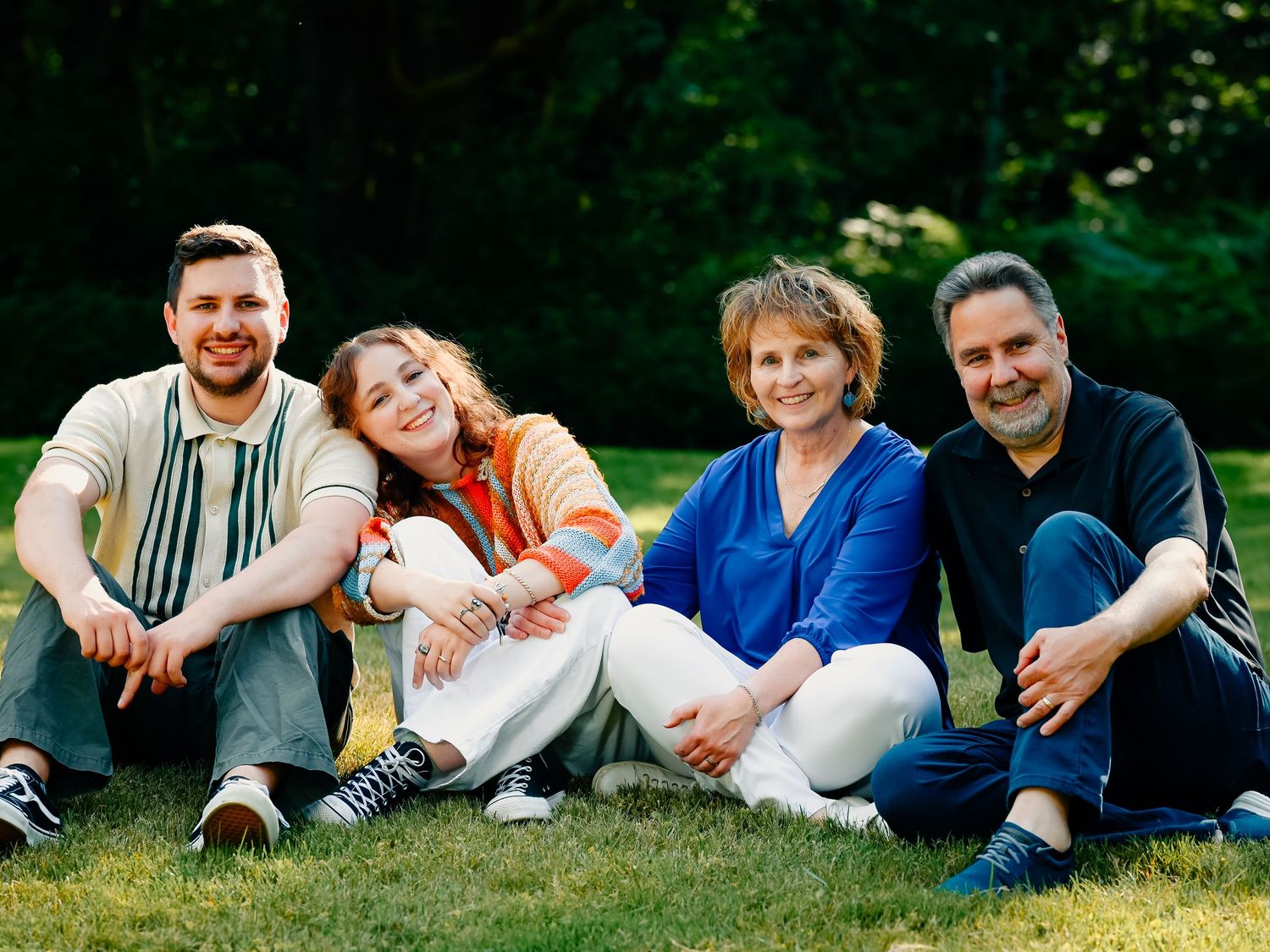 Group of people lounging on grass during outdoor family photo session.