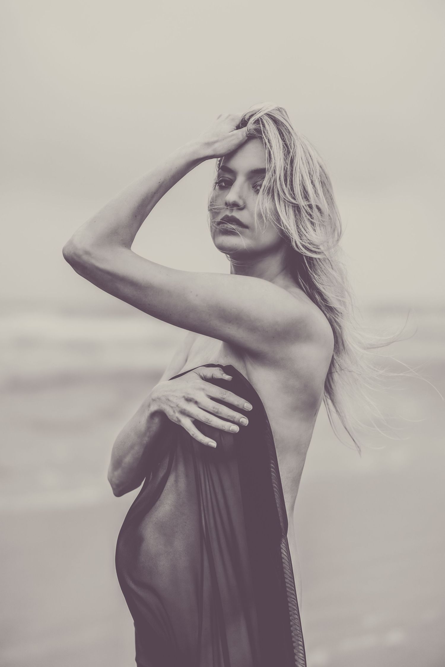 Artistic portrait of woman in draped fabric against muted background.