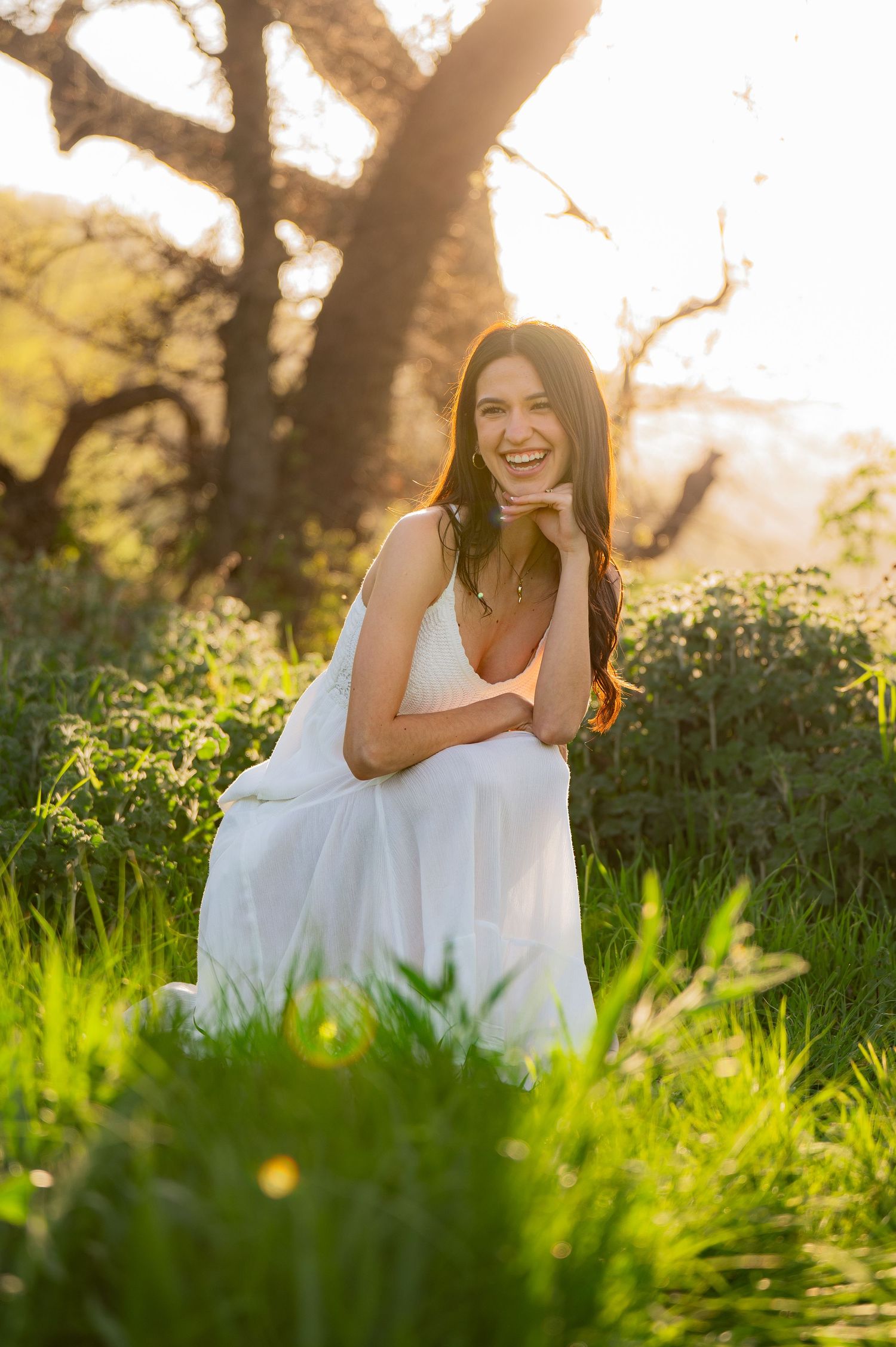 Someone in a flowing white dress relaxes in sunlit grass.