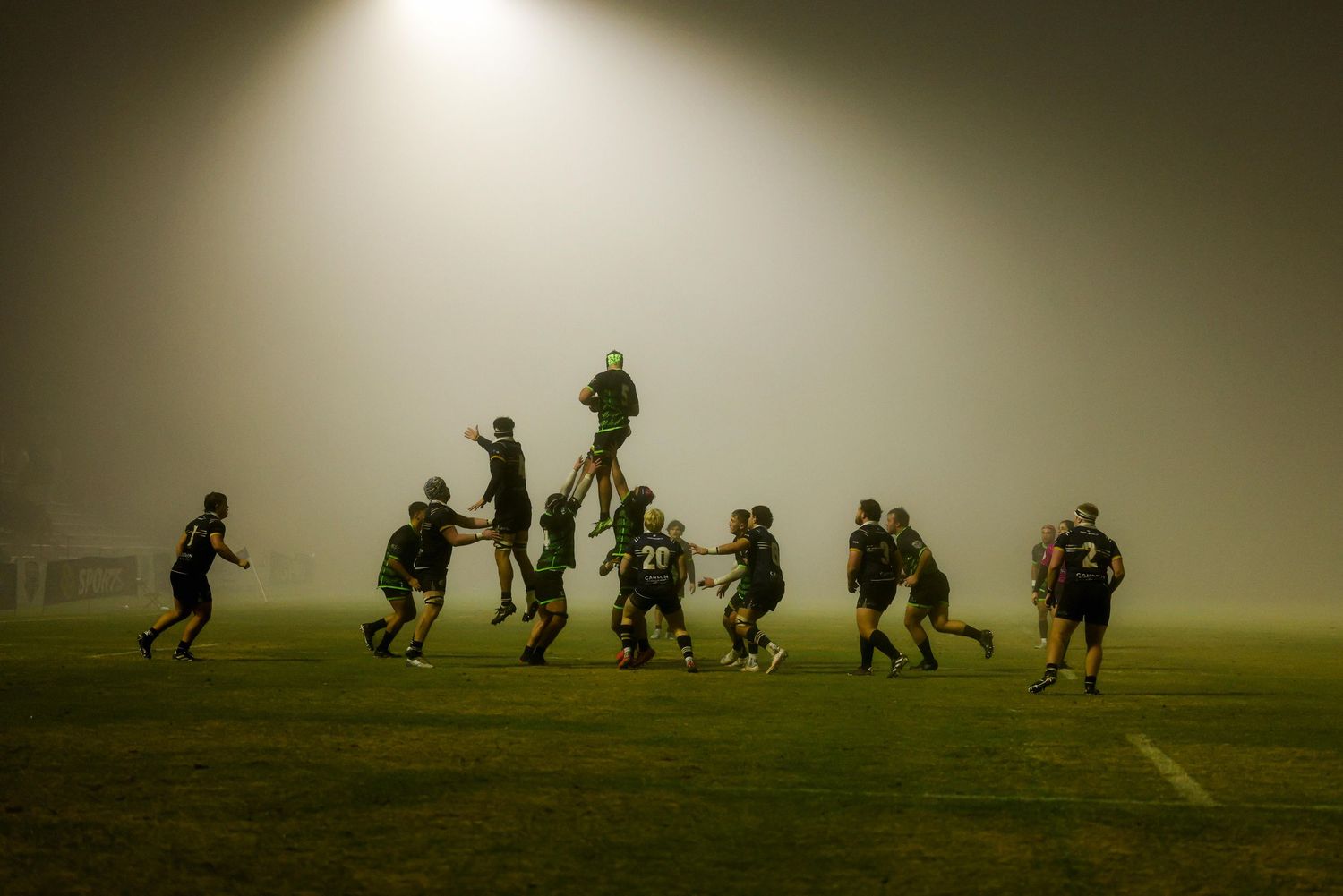 Team sports photography capturing athletes in low fog during live match, creating dramatic atmosphere for sports media and brand imagery