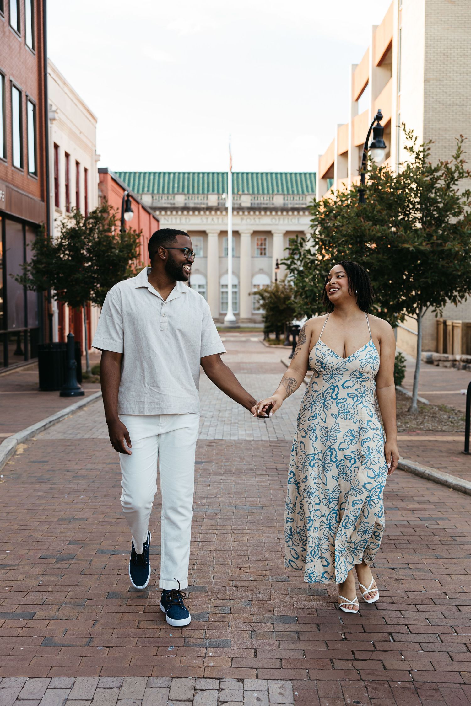 Couple walking and laughing together on brick paved street in front of historic buildings.
