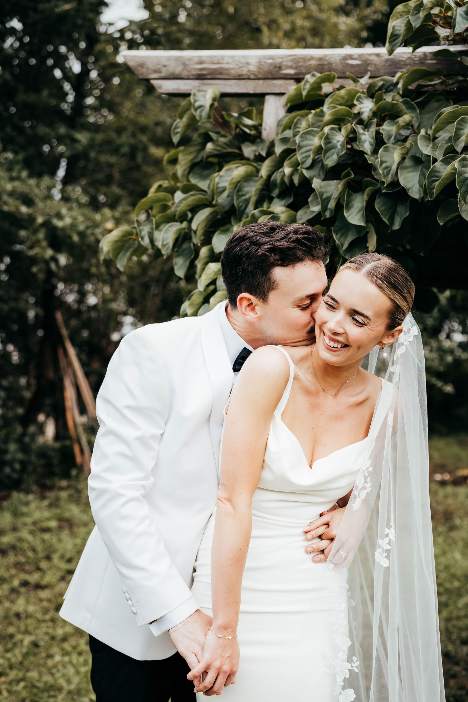 A romantic wedding moment captured in a garden setting with greenery.
