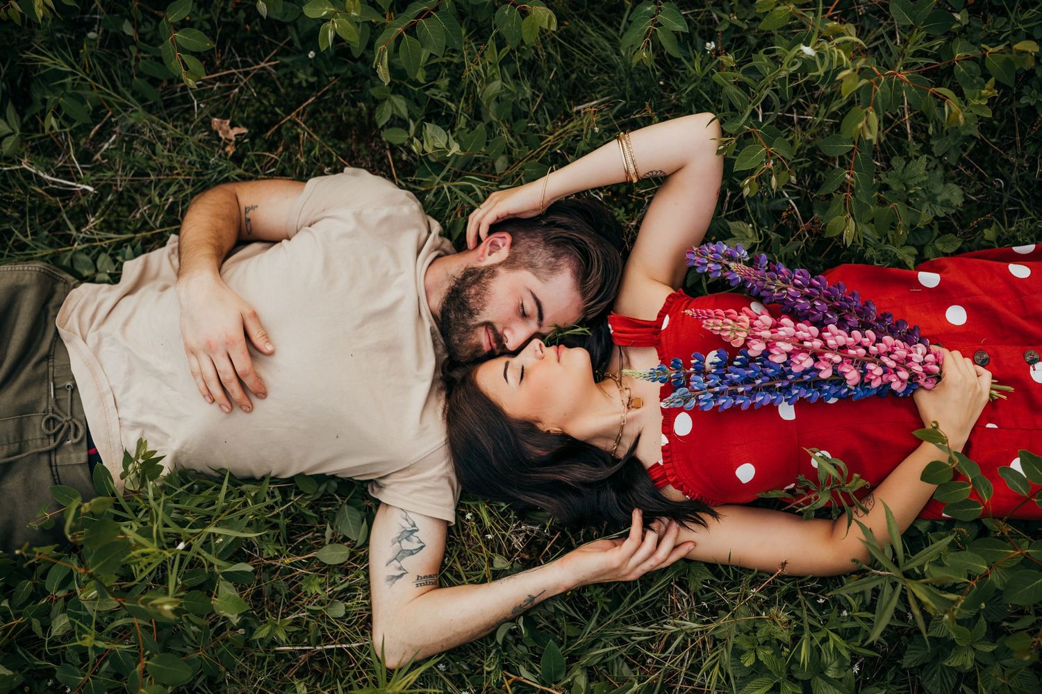 Couple lying in garden sharing intimate moment surrounded by greenery.