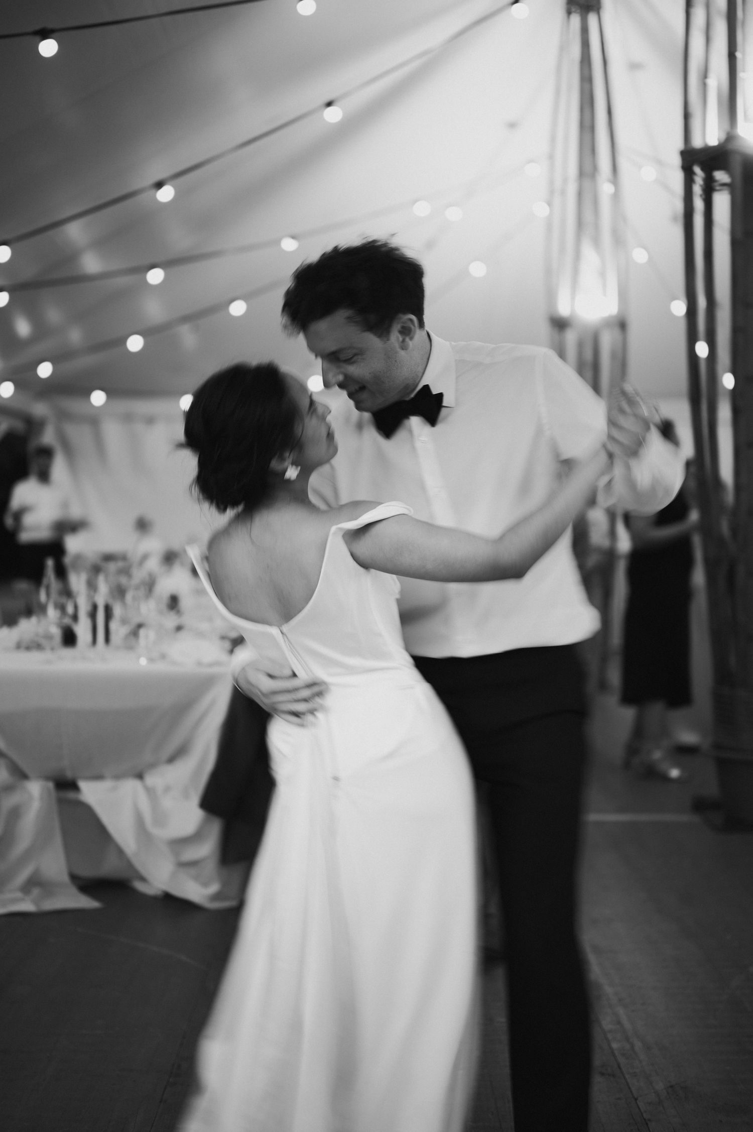 Romantic dance sequence under twinkling lights in a wedding reception tent.