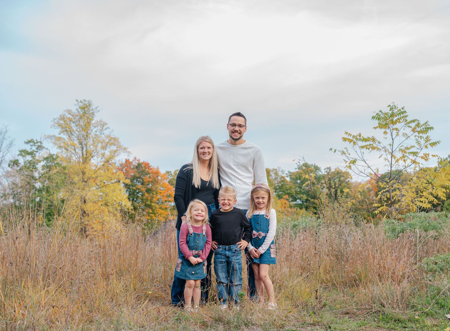 family posing for camera in pretty fall field