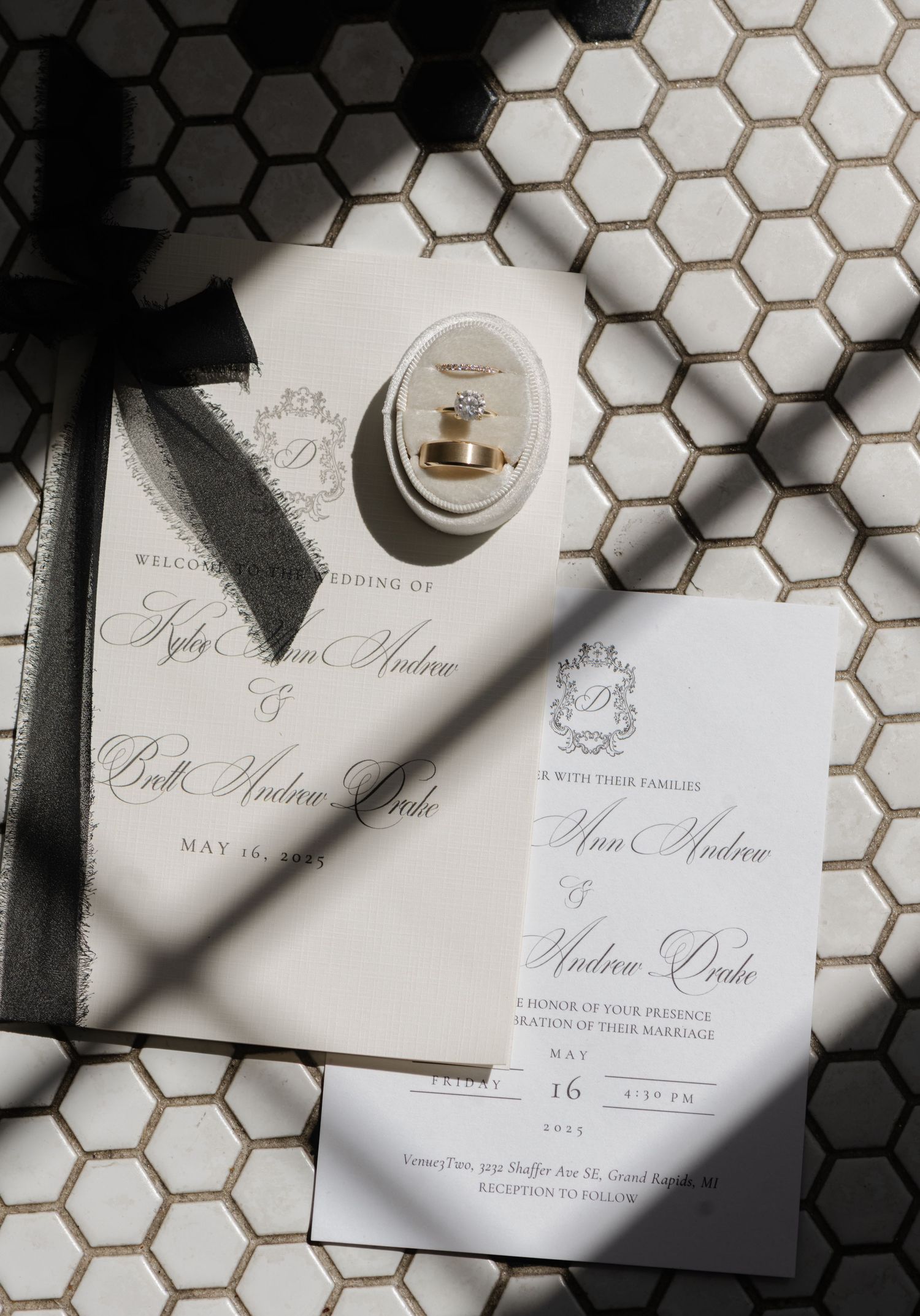 detail shot of wedding rings and invites on tile floor at venue three two