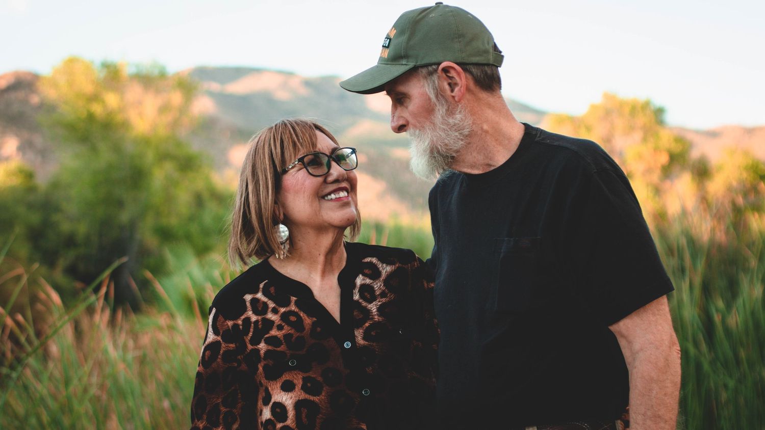 Couple sharing joyful moment together during sunset in natural outdoor setting.