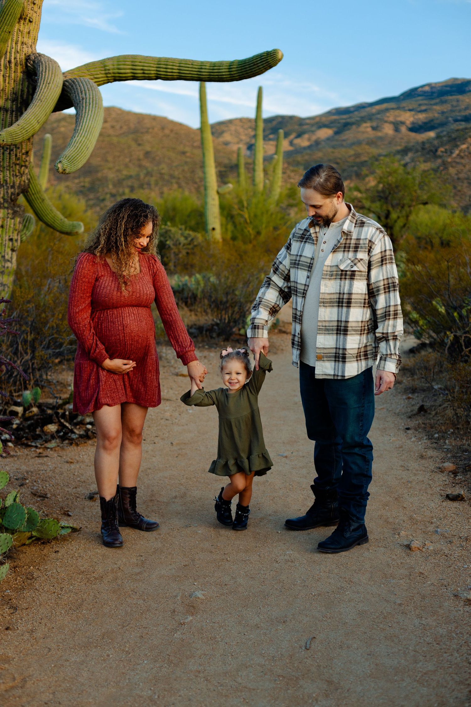 Family walking together among saguaro cacti in the desert at sunset.