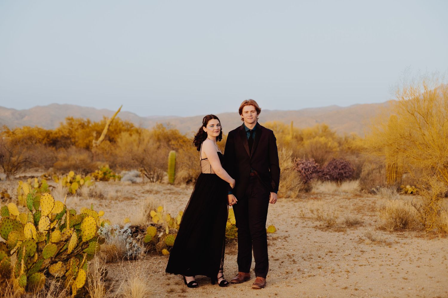 Couple walking through desert landscape during golden hour.