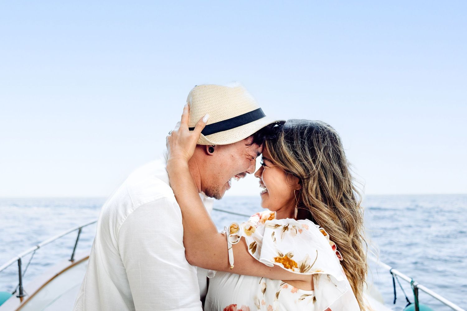 Intimate moment between couple on sailboat against ocean backdrop.