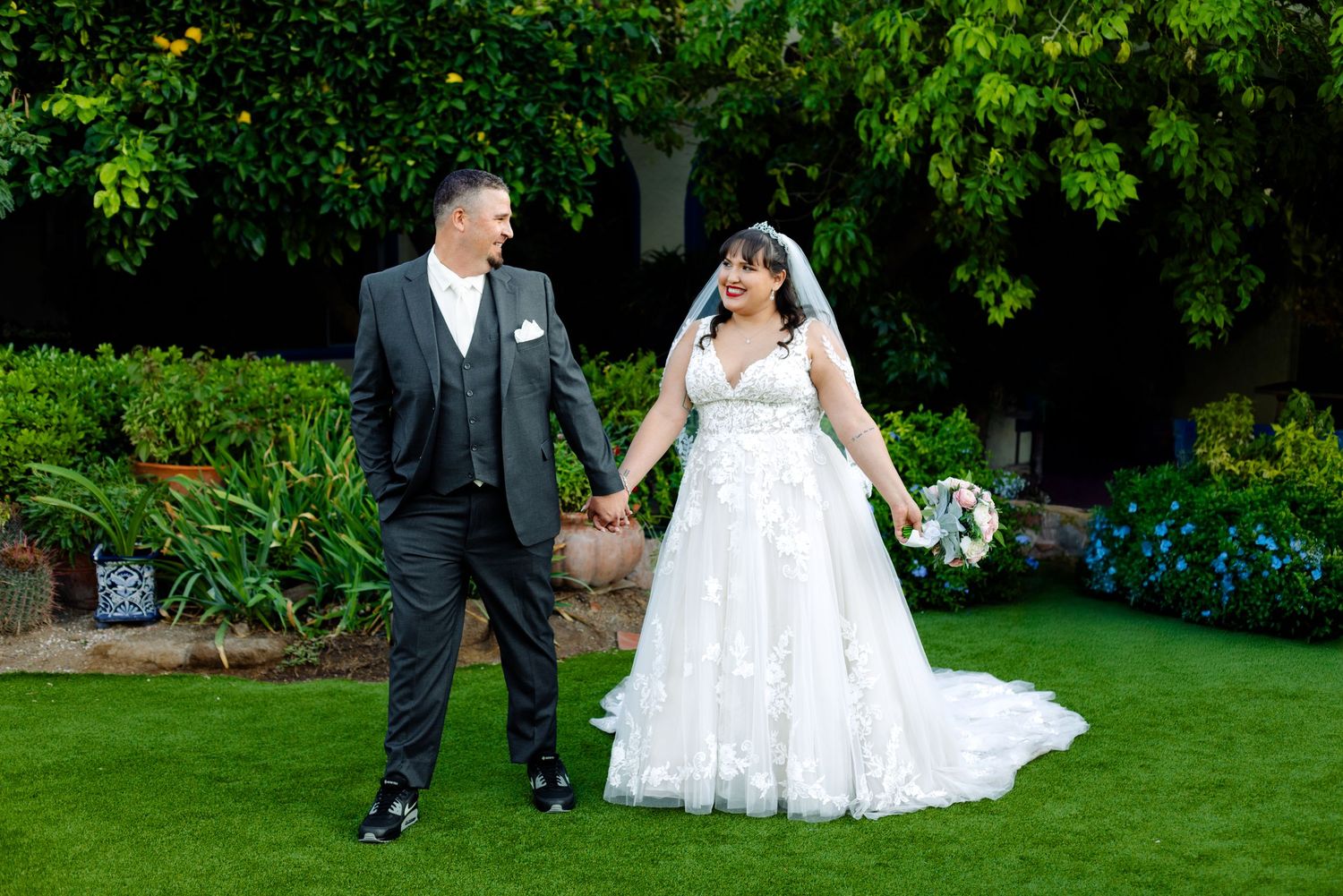 A wedding couple poses on lush green grass for outdoor photos.