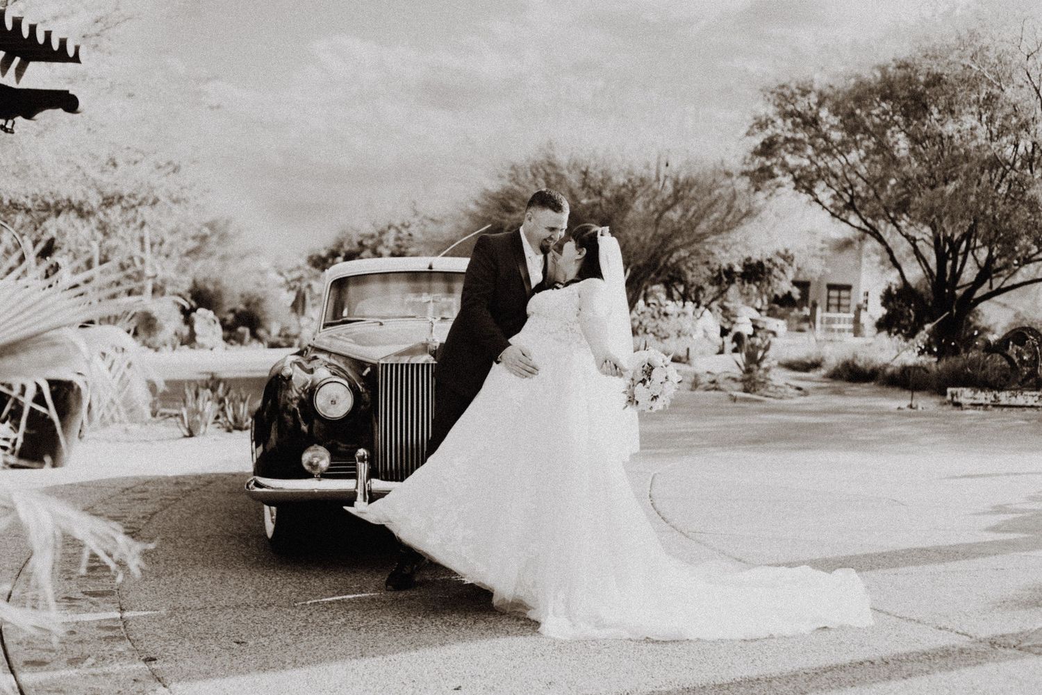 Classic black and white wedding photo with vintage car in background.
