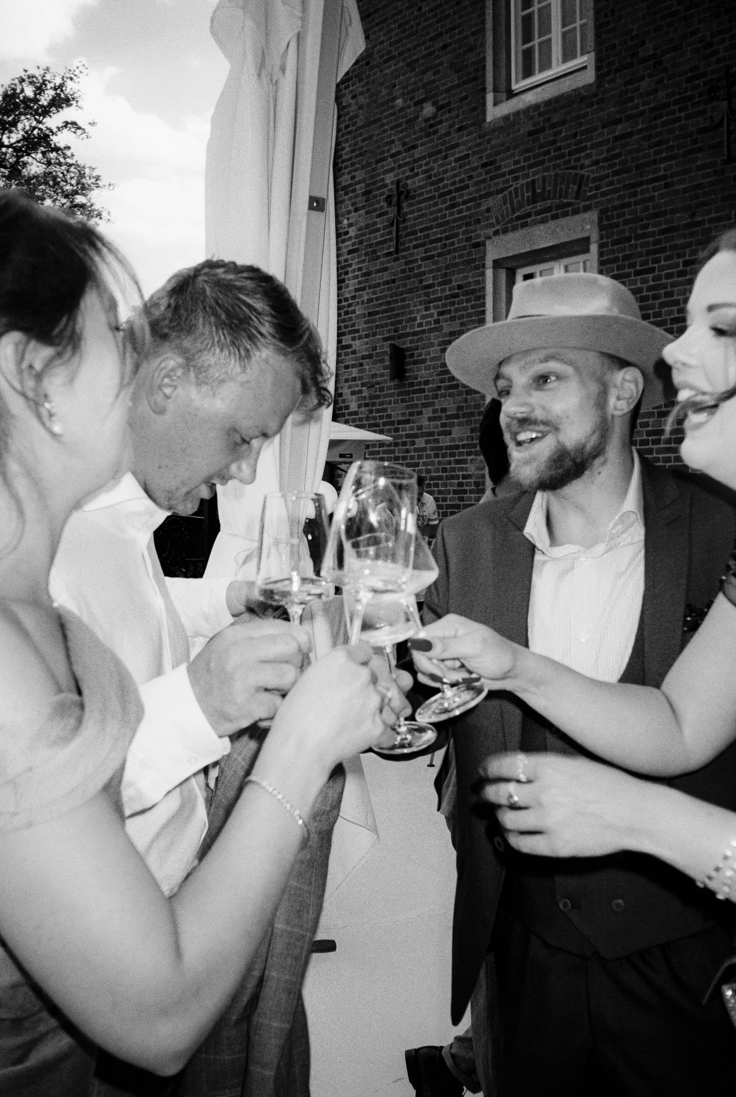 Black and white photo of wedding guests toasting with wine glasses at a celebration.