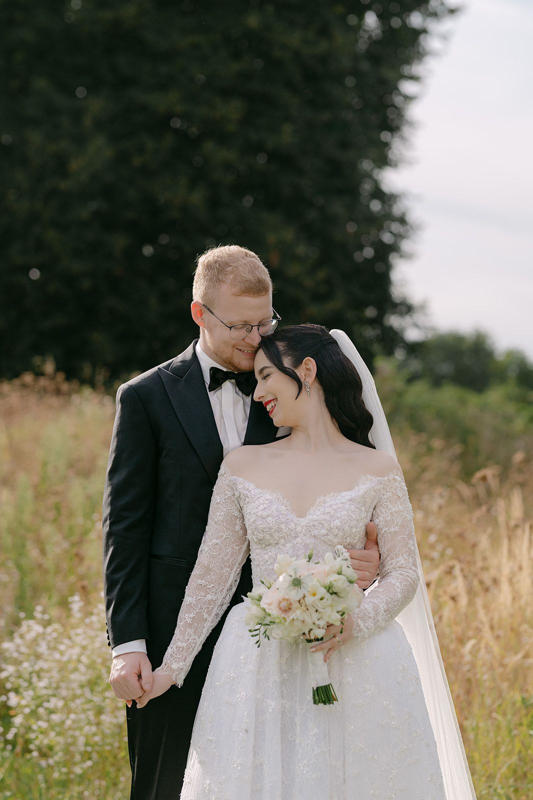 Romantic outdoor wedding portrait of a couple standing in a wildflower field.
