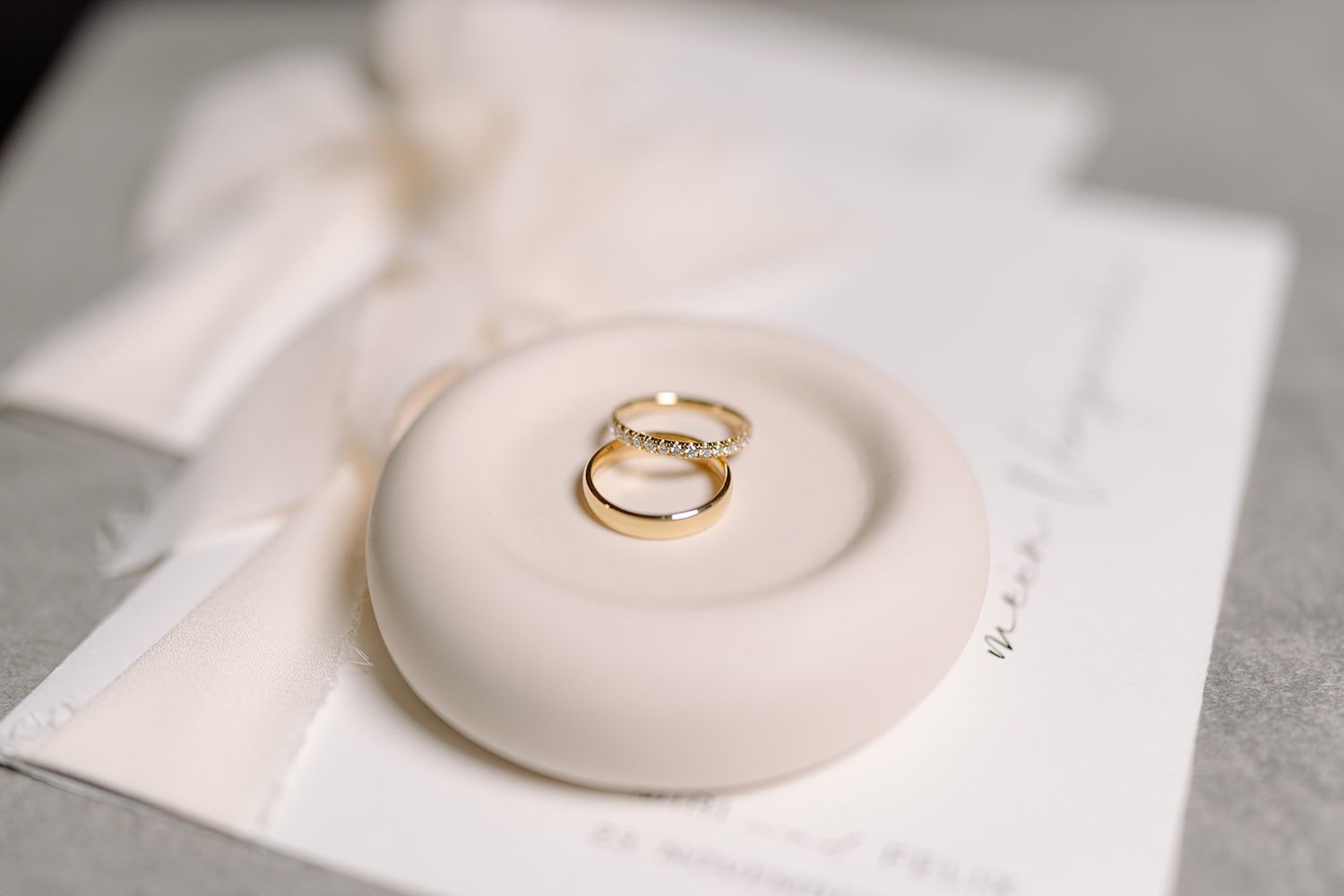 Close-up of wedding rings displayed on a white ceramic dish.