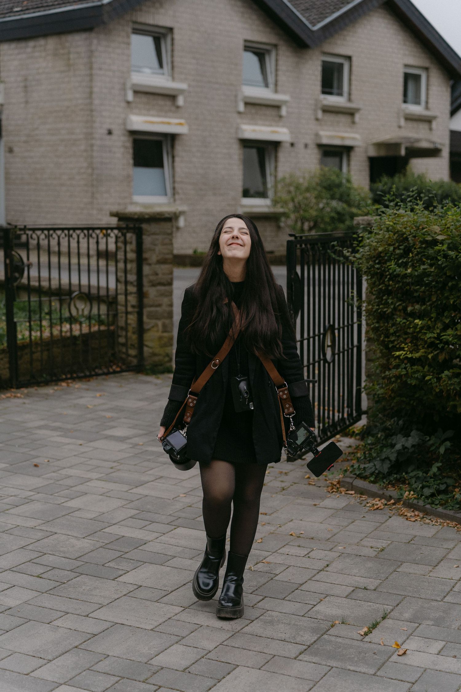Person walking along a stone pathway outside a brick building with metal railings.