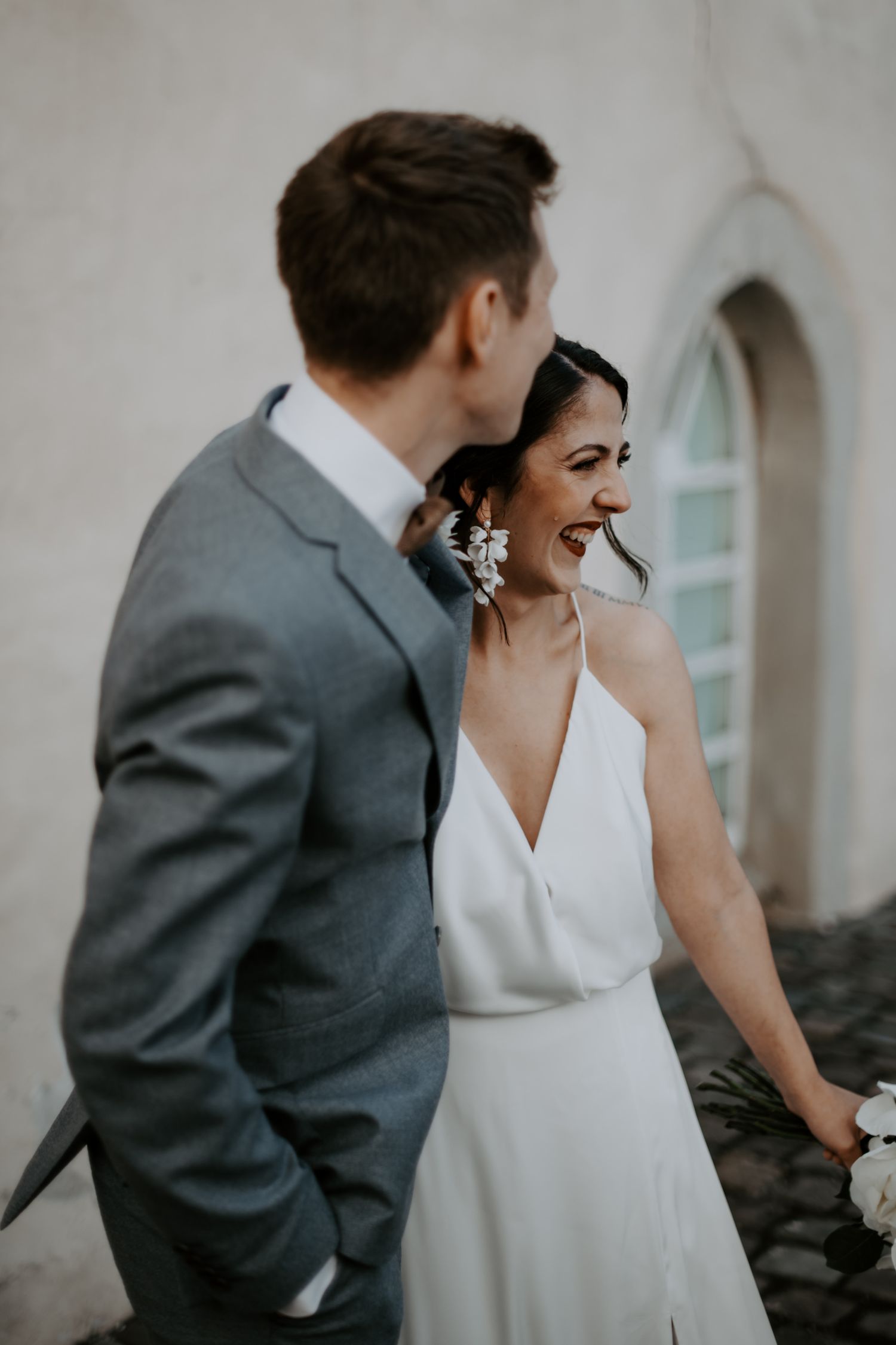 A joyful wedding couple sharing a candid laughing moment together in black and white.
