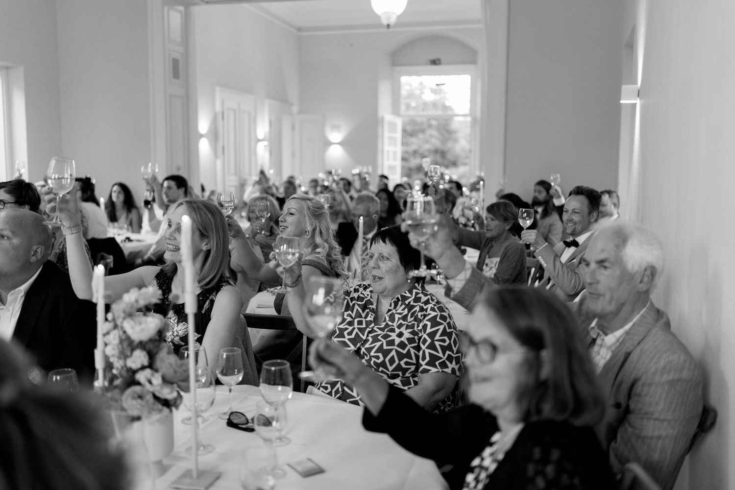 Wedding reception panorama showing guests seated in an elegant white banquet hall.