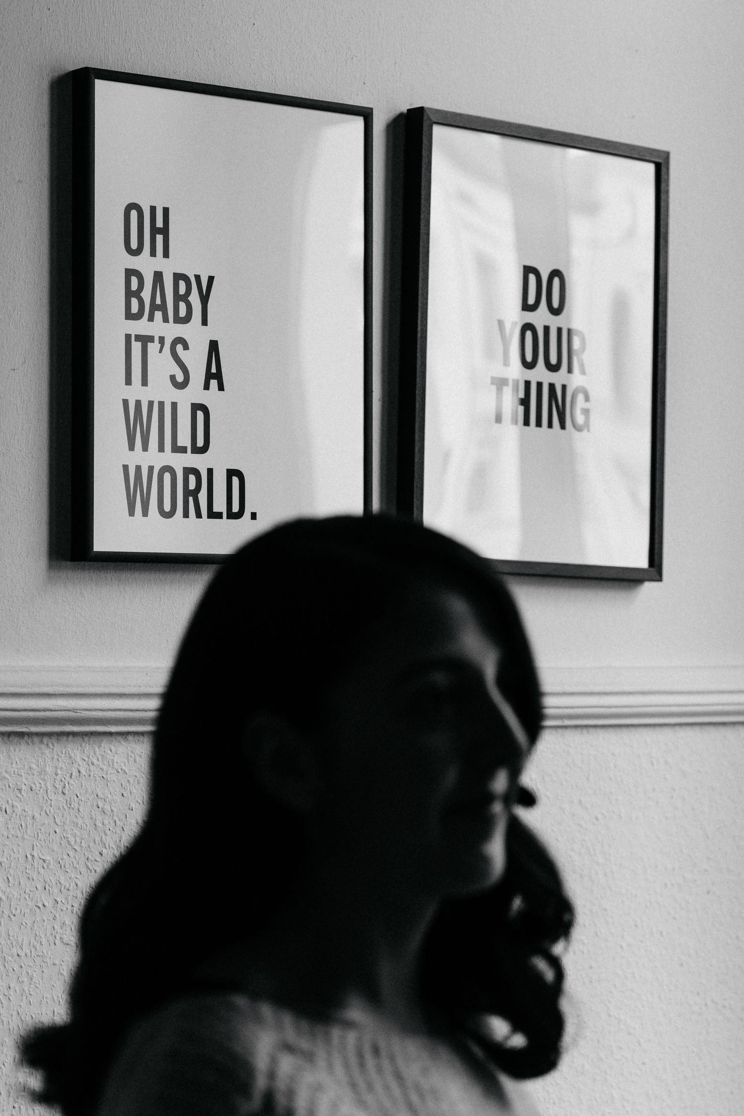 Black and white photo of a silhouette against wall art with motivational text quotes.