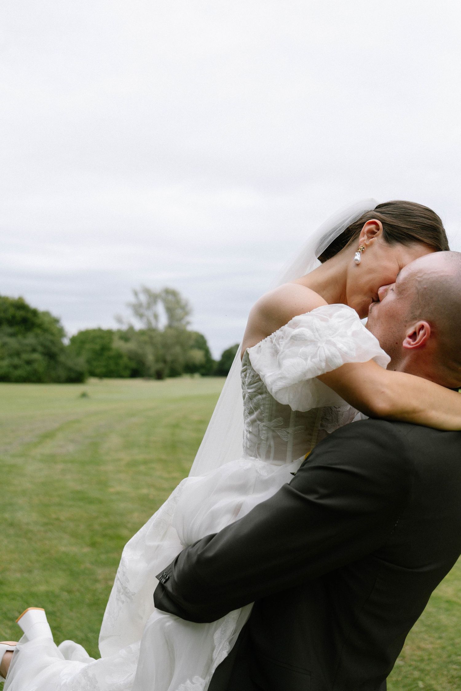 Candid wedding moments captured in an open field with natural lighting.