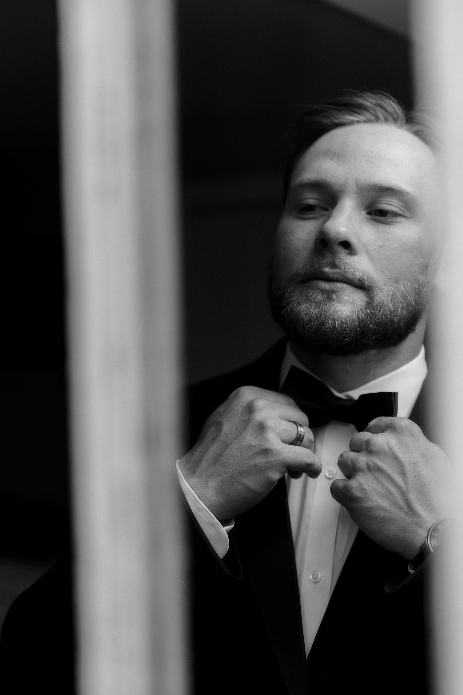 Mirror photo of groom fixing bow tie at Kamloops Courthouse, capturing stylish, elegant, and detailed wedding preparation photography.