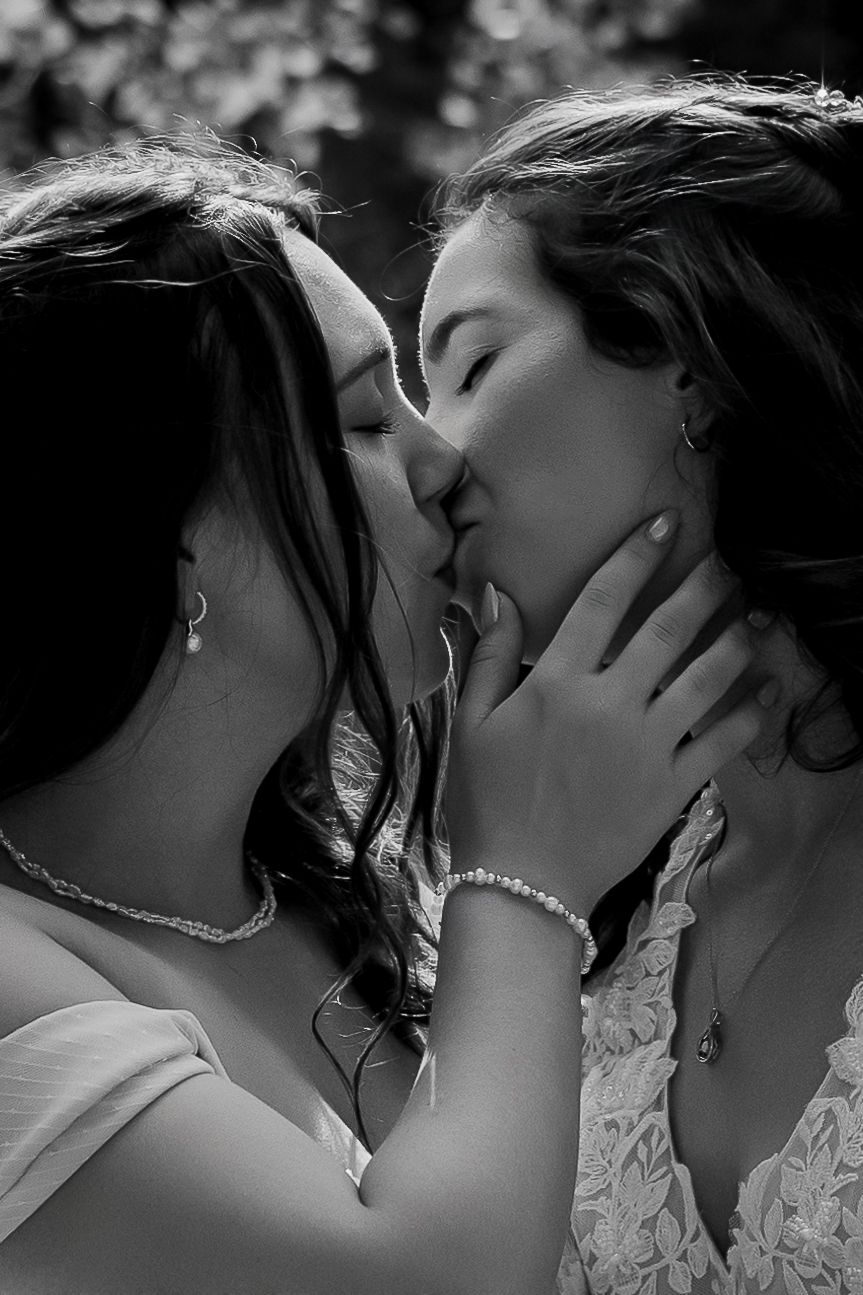 Black and white luxury wedding photo of same-sex couple kissing, capturing romantic, intimate, and stylish LGBTQ+ wedding photography.
