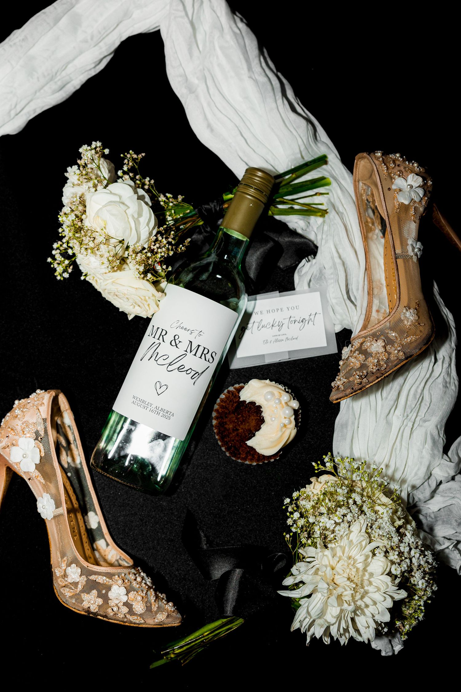 Luxury wedding evening flat lay with eaten cake, wine bottle, bridal shoes, and drink tickets, capturing stylish wedding details and decor.
