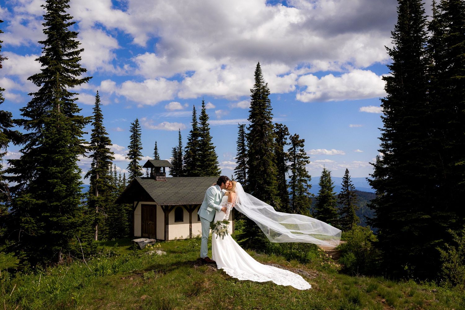 Wedding portrait of couple kissing on top of a mountain at Sun Peaks Resort, capturing love and intimacy in true-to-colour photography.