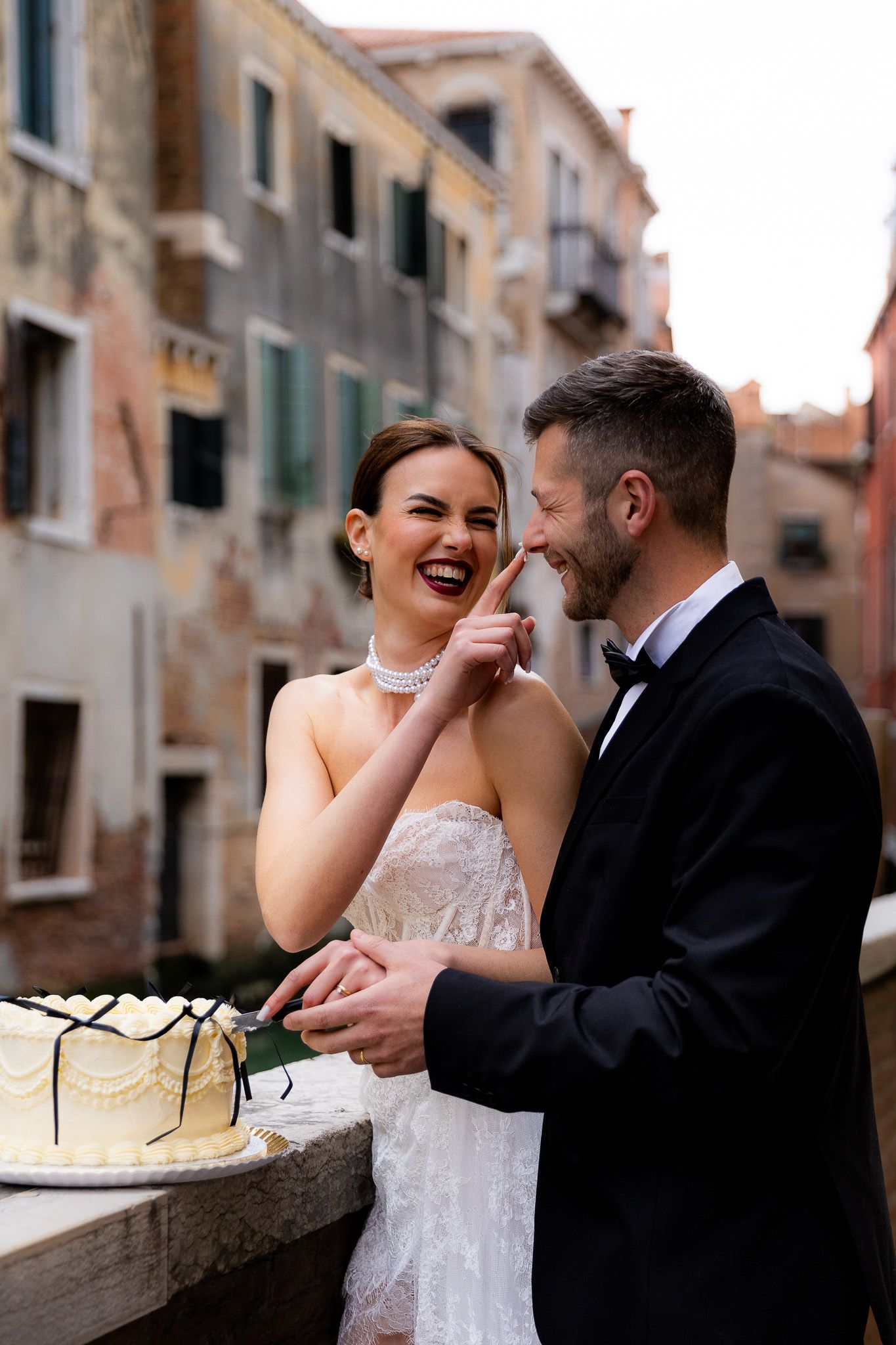 Bride and groom cutting their wedding cake along the Venice canals, captured by a professional wedding photographer, capturing unique moment