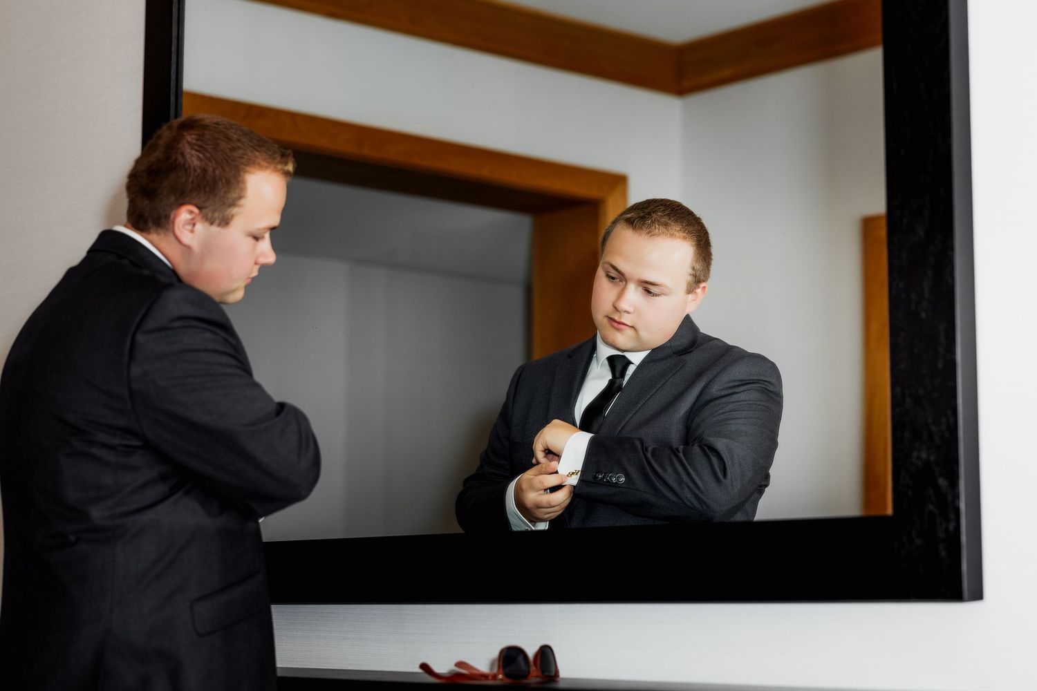 Candid luxury wedding photo of groom touching up in mirror, capturing stylish and elegant wedding preparation moments in detail.
