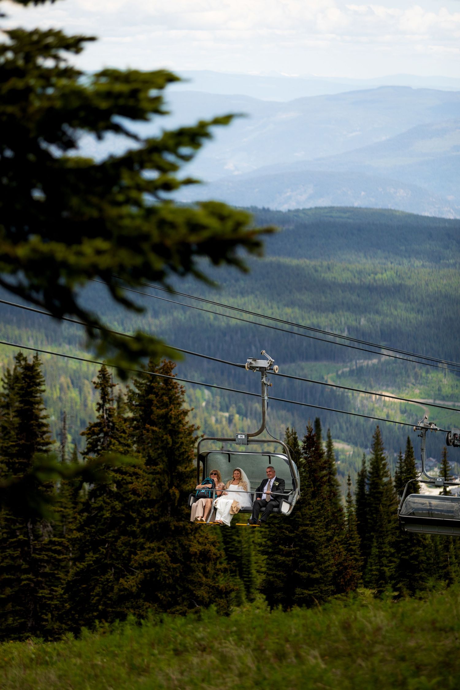 Dramatic luxury wedding photo of bride riding chairlift to ceremony at Sun Peaks, capturing stunning mountain views and stylish wedding vibe