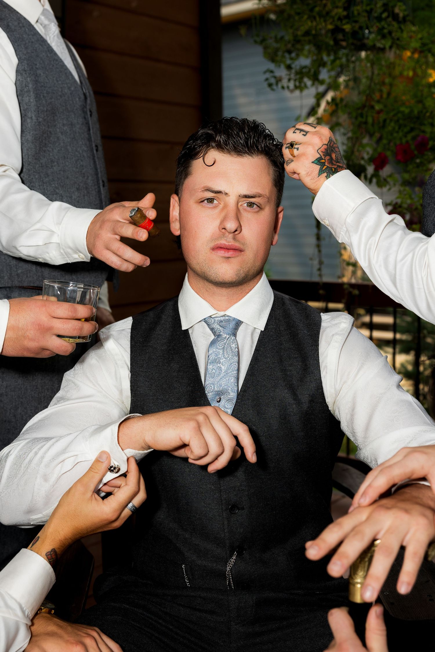 Groom having his details adjusted by groomsmen, GQ style, capturing stylish and elegant wedding preparation photography.