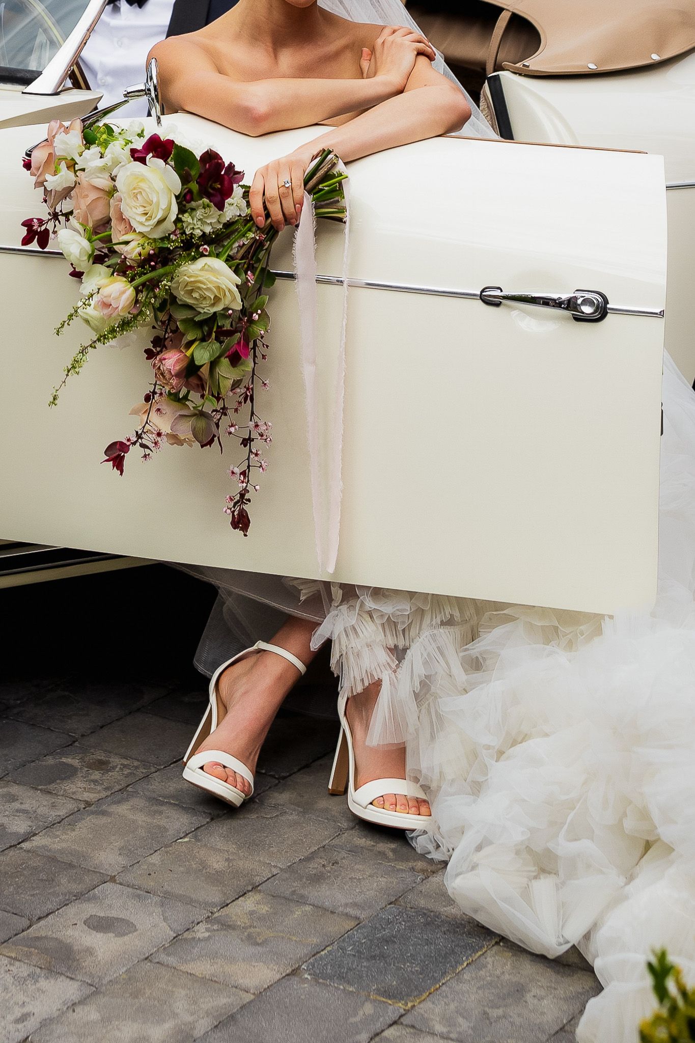 Luxe wedding detail photo of bride’s shoes and bouquet by vintage Porsche in Kelowna, capturing stylish and elegant wedding photography.