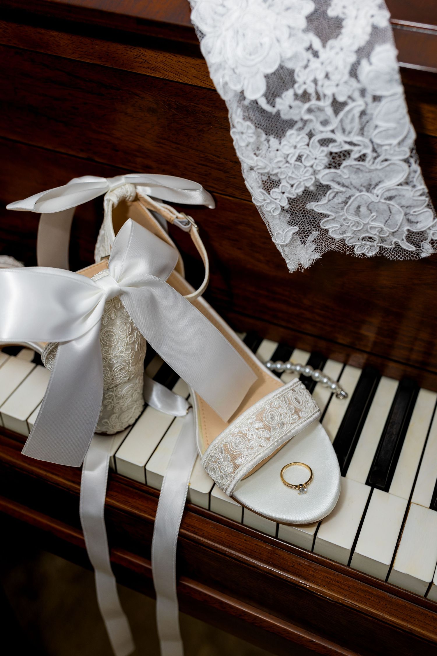 Luxury wedding detail photo of bride’s shoes, ring, and gloves on piano, capturing elegant and stylish bridal accessories photography.
