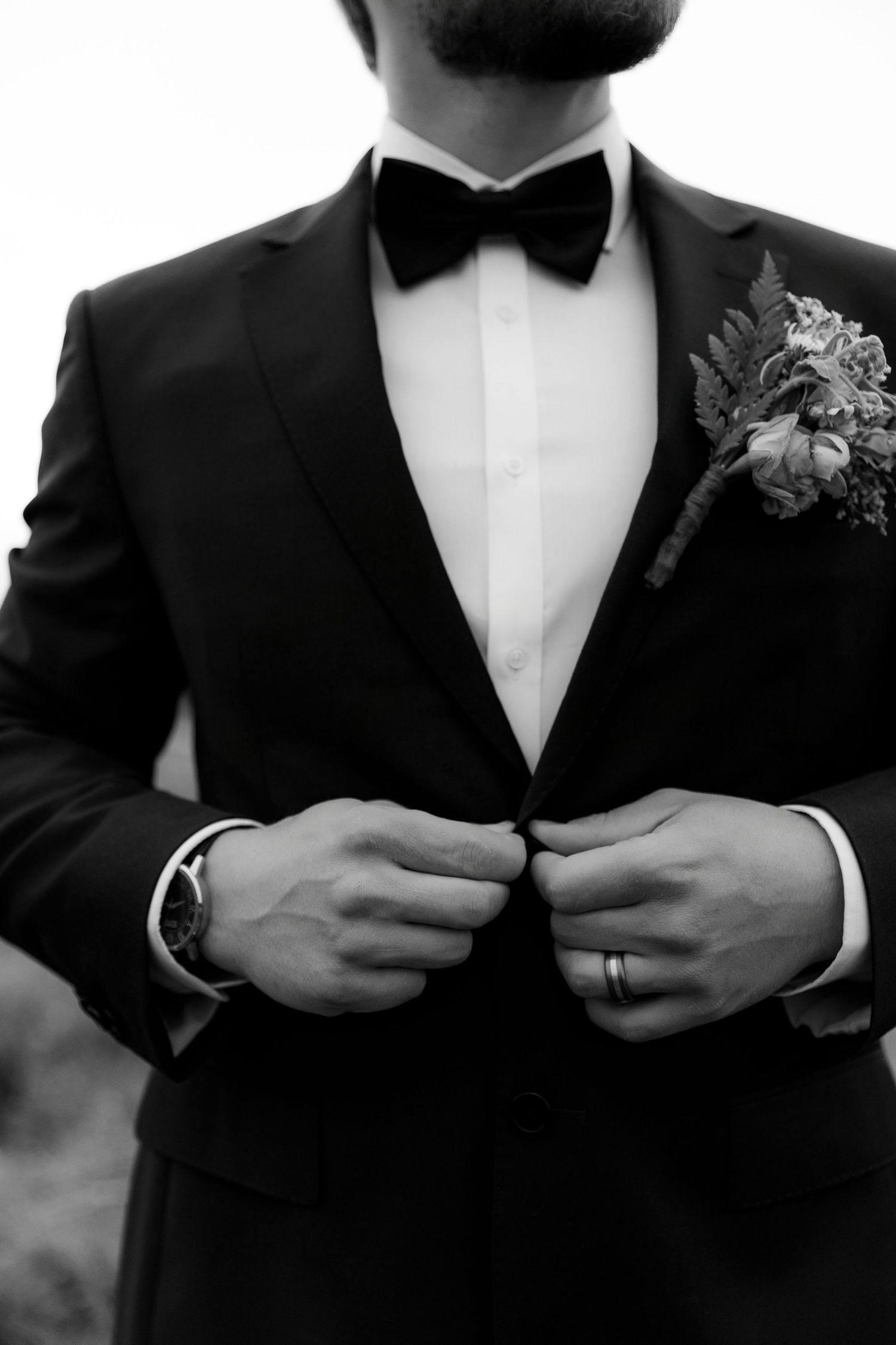 Luxury wedding photo of groom buttoning suit jacket in Kamloops, capturing stylish, elegant, and detailed wedding preparation photography.