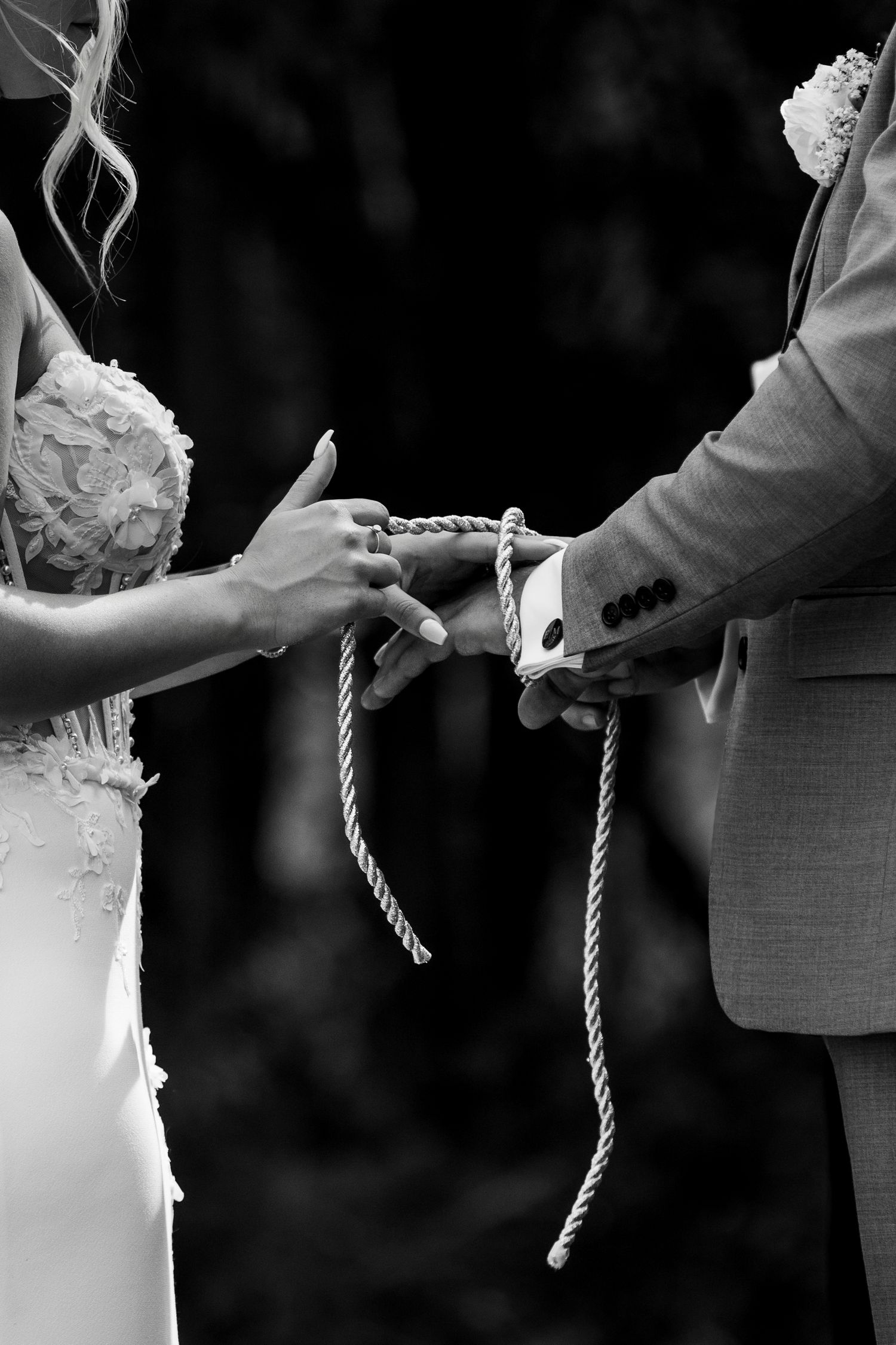 Luxury wedding photo of bride and groom tying knot around hands during ceremony in Grande Prairie, capturing intimate wedding moments.