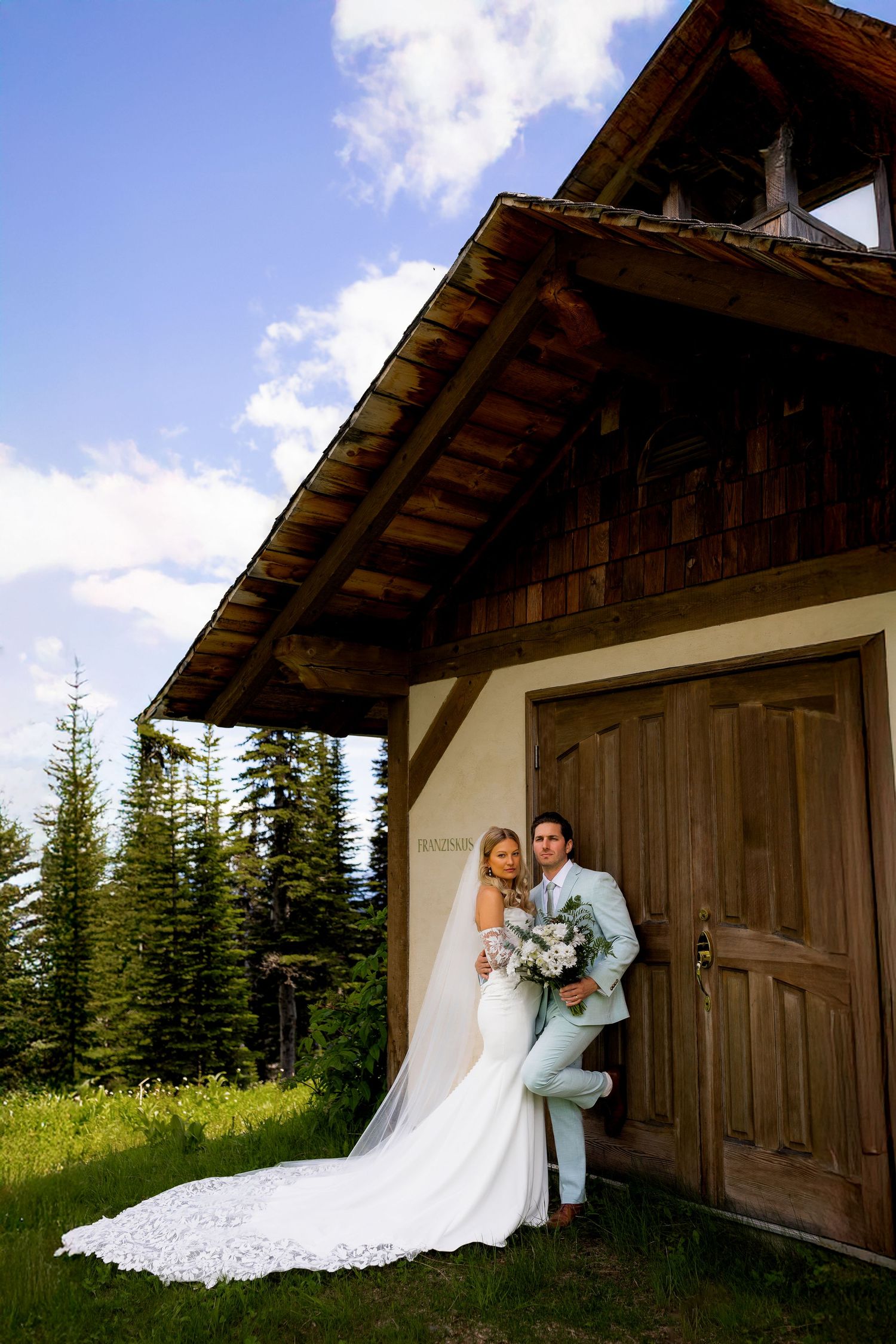 Luxury wedding photo of newlyweds standing outside a church at Sun Peaks Resort, capturing stylish destination wedding photography.