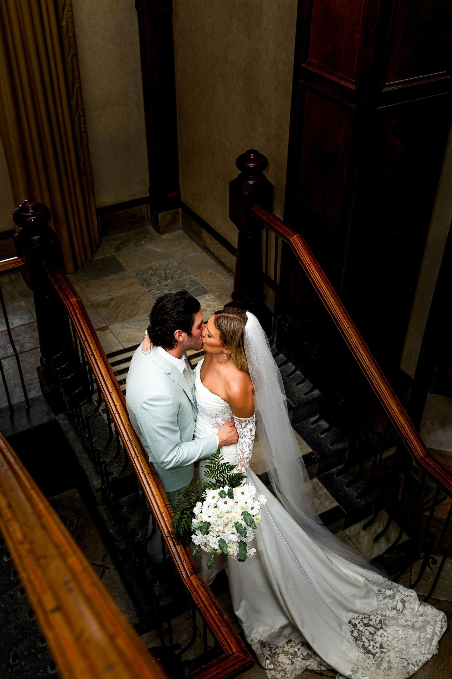 Romantic wedding photo of newlyweds kissing on staircase at Sun Peaks Grand Hotel, capturing intimate, stylish destination wedding moment.