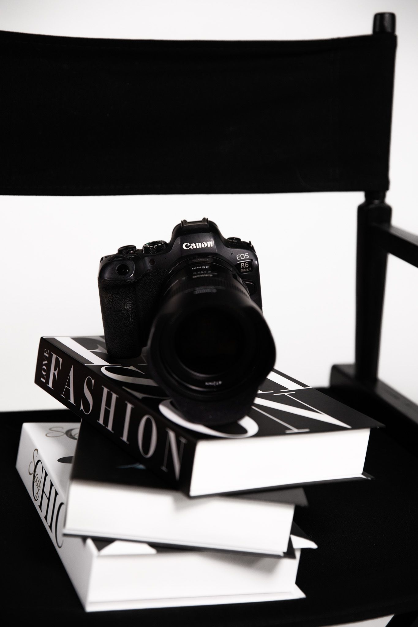 Photographer in a power suit with glam makeup, sitting surrounded by branded photos and logo, showcasing luxury photography and branding.