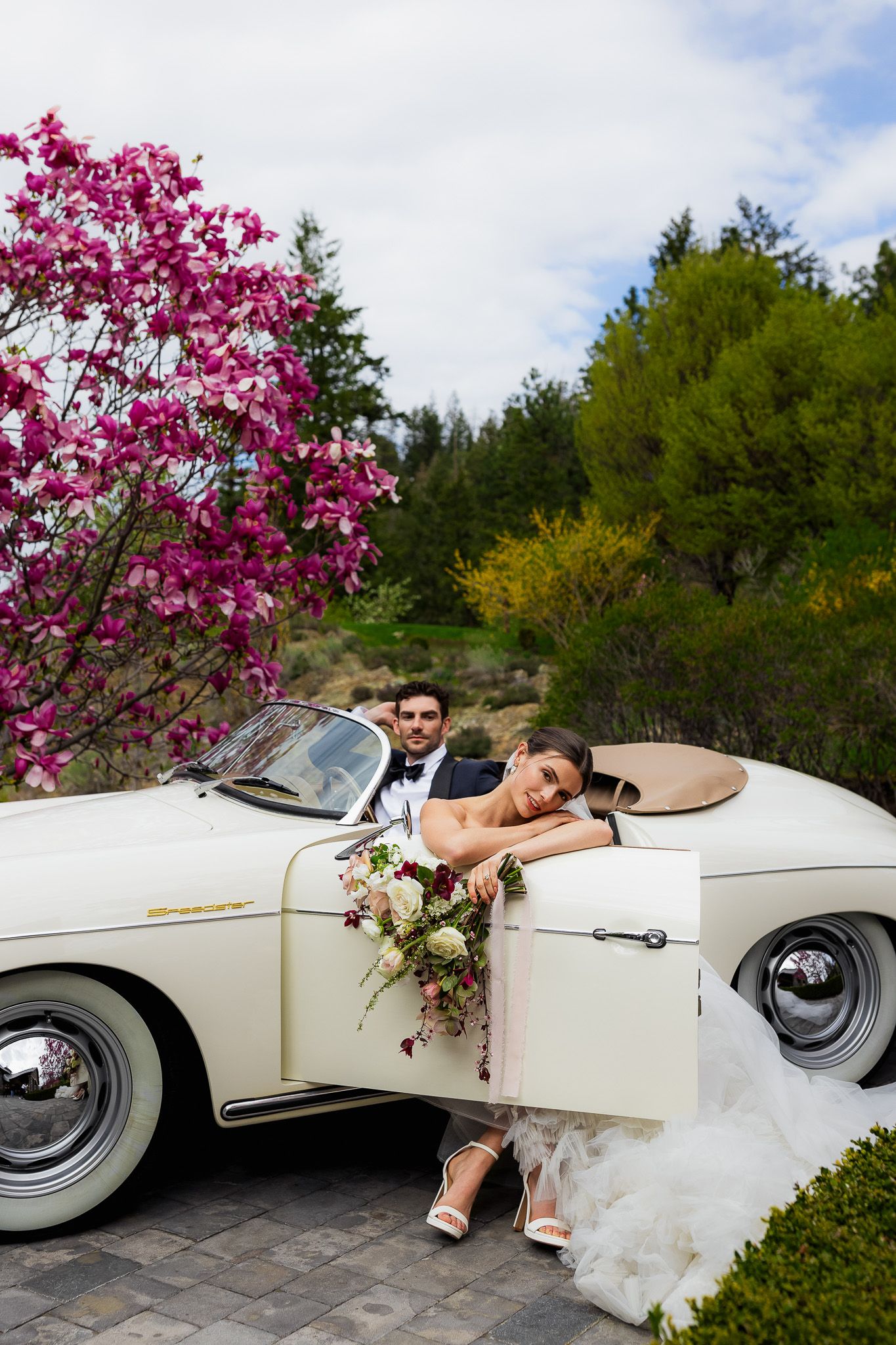 Luxury wedding photo of bride and groom sitting in vintage Porsche at Kelowna venue, capturing stylish and romantic wedding photography.