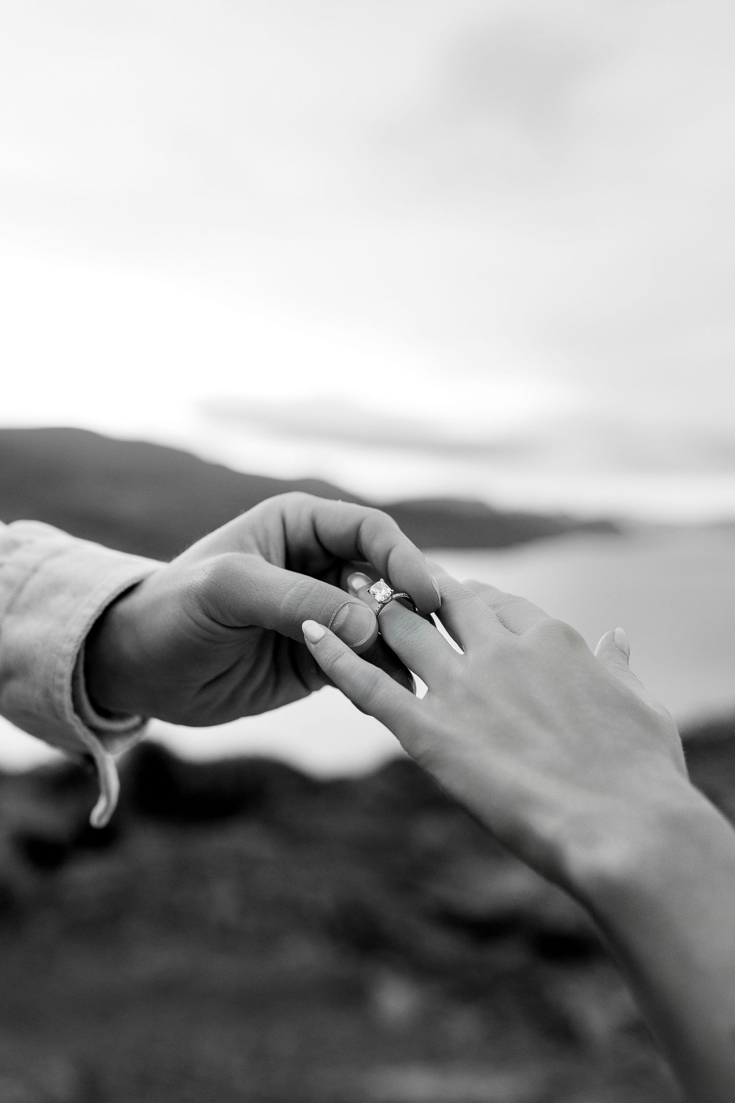 Romantic engagement photo of man placing ring on woman’s finger overlooking Kamloops Lake, luxury engagement and destination photography.